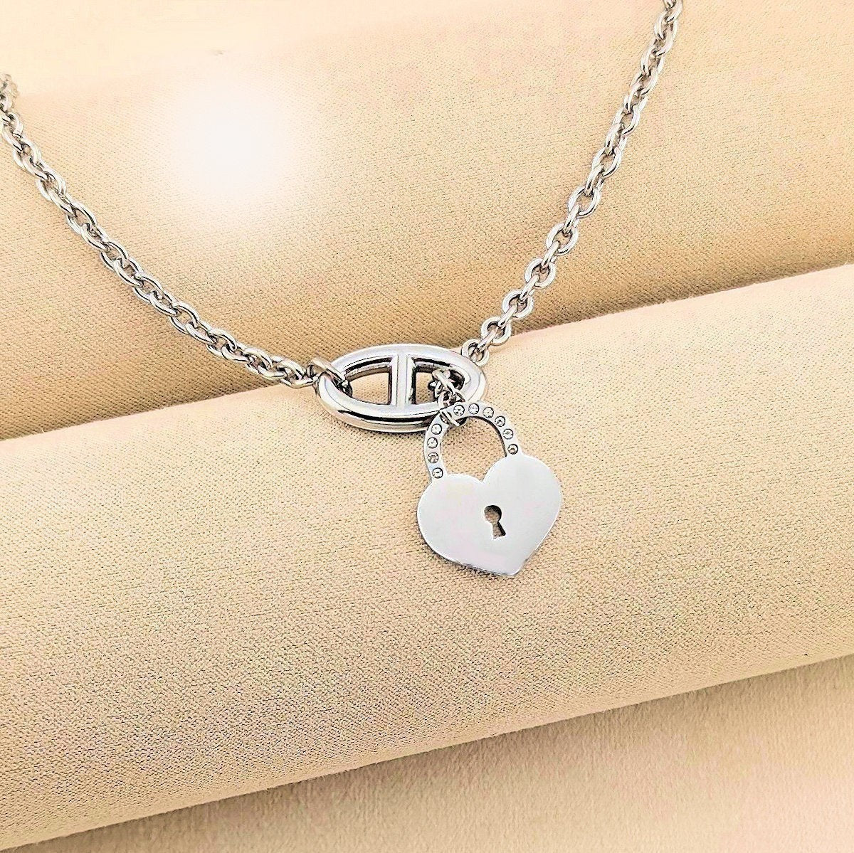 Ninky Designs Australia silver heart padlock pendant necklace on a beige fabric background.
