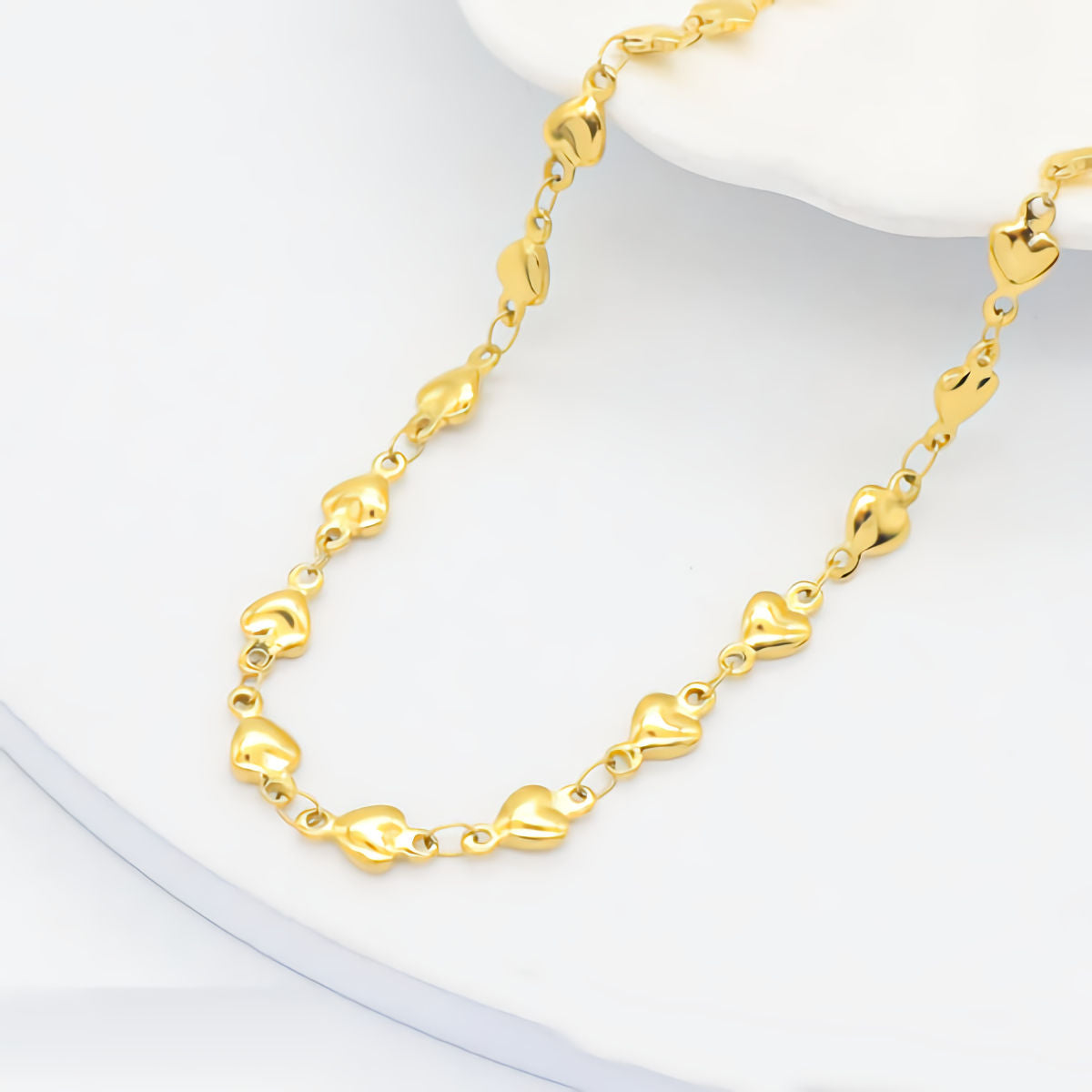 Gold bracelet with heart-shaped links on a white background