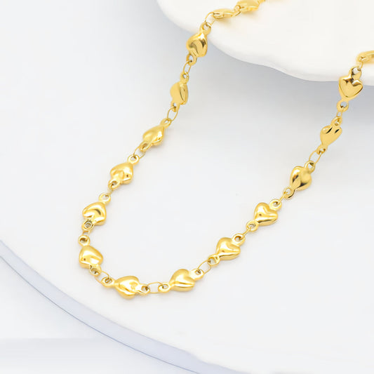 Gold bracelet with heart-shaped links on a white background