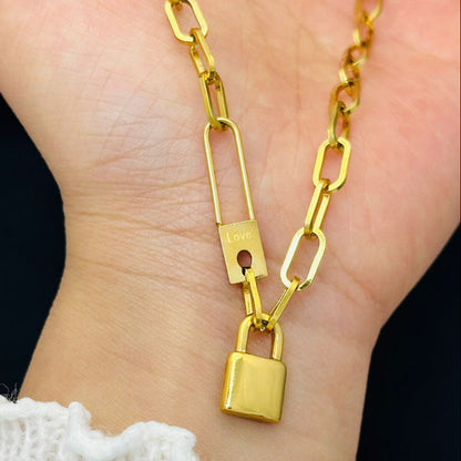 Gold chain necklace with a padlock pendant on a hand against a dark background