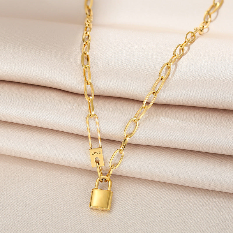 Gold chain necklace with a padlock pendant on a beige fabric background