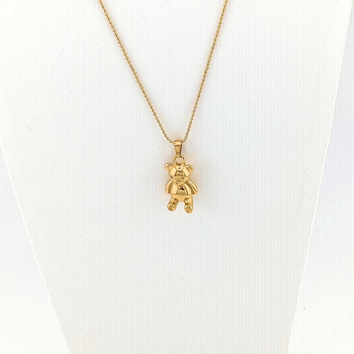 Gold teddy bear pendant necklace on a white background