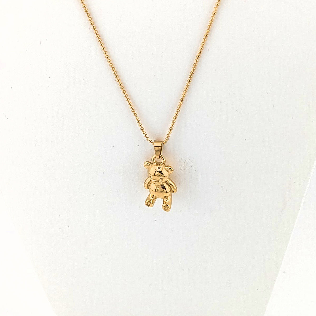 Gold teddy bear pendant necklace on a white background