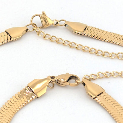 Close-up of a gold-tone chain necklace with a textured snake-link style band and lobster clasp on a white background.