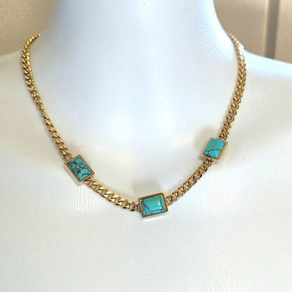 Gold chain necklace with turquoise square stones on a mannequin.