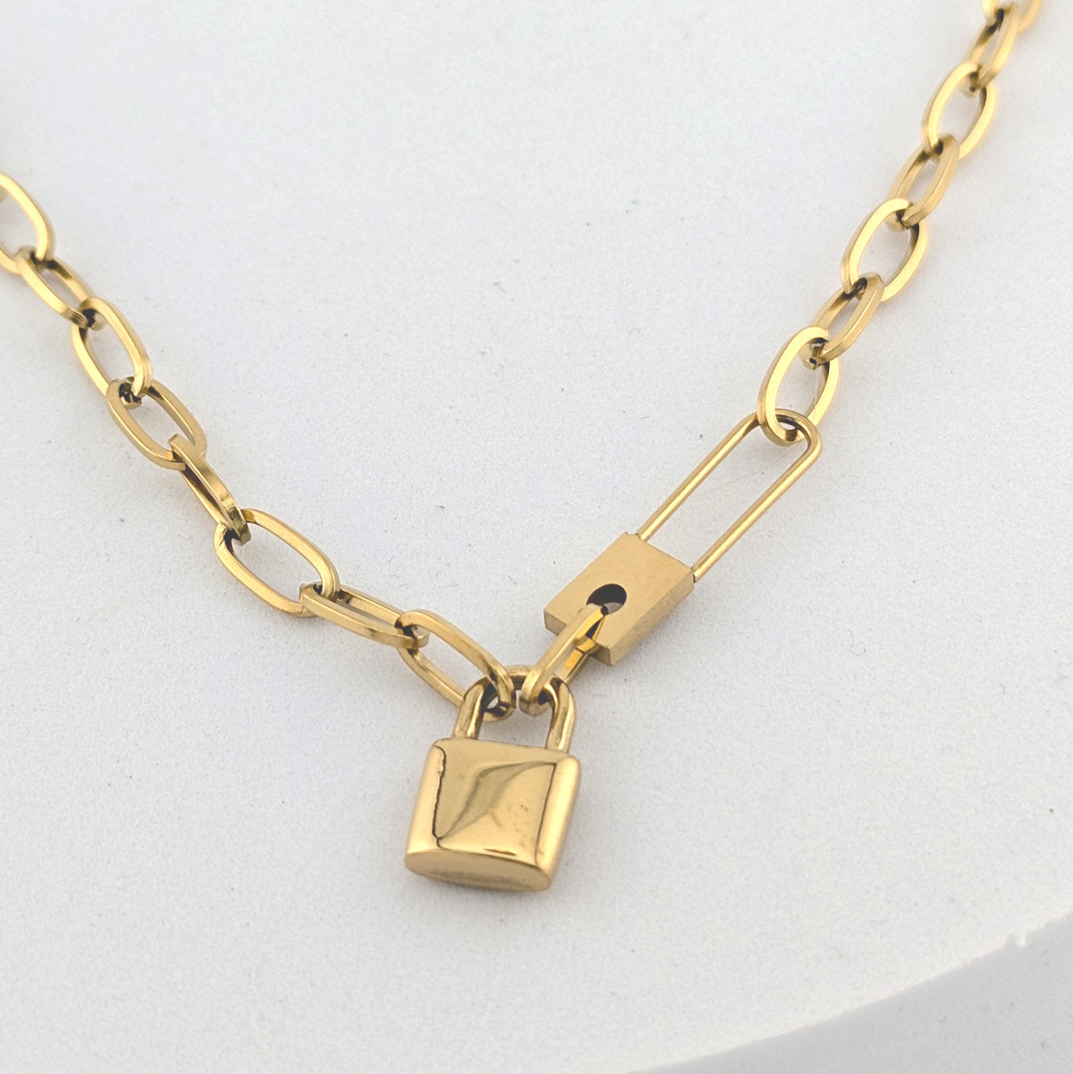Gold chain necklace with a lock pendant on a white background