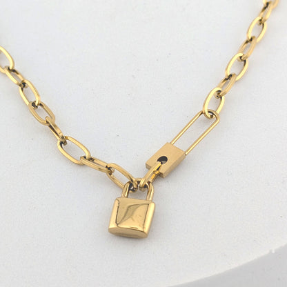 Gold chain necklace with a lock pendant on a white background