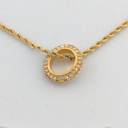Gold necklace with a heart-shaped pendant on a light gray background