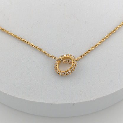 Gold necklace with a circular pendant on a white background