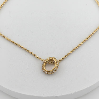 Gold necklace with a circular pendant on a light gray background