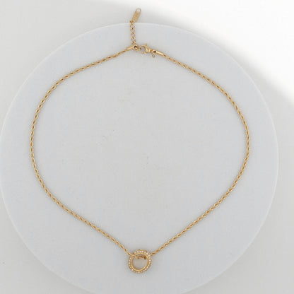 Gold necklace with a small round pendant on a white background