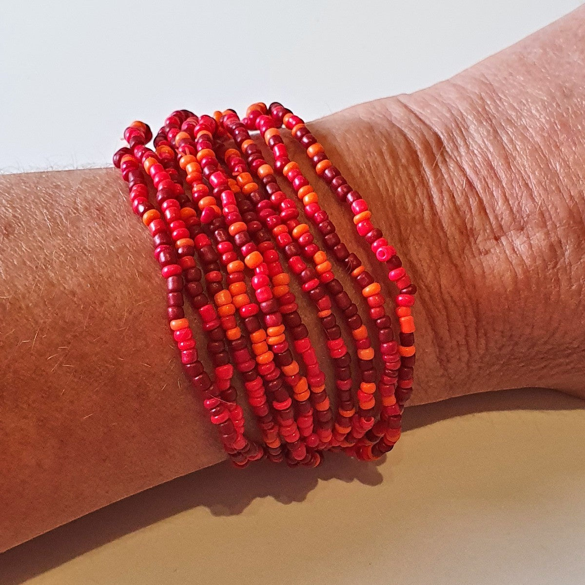 Ninky Designs Australia stretch seed bead bracelets in shades of red worn on a wrist
