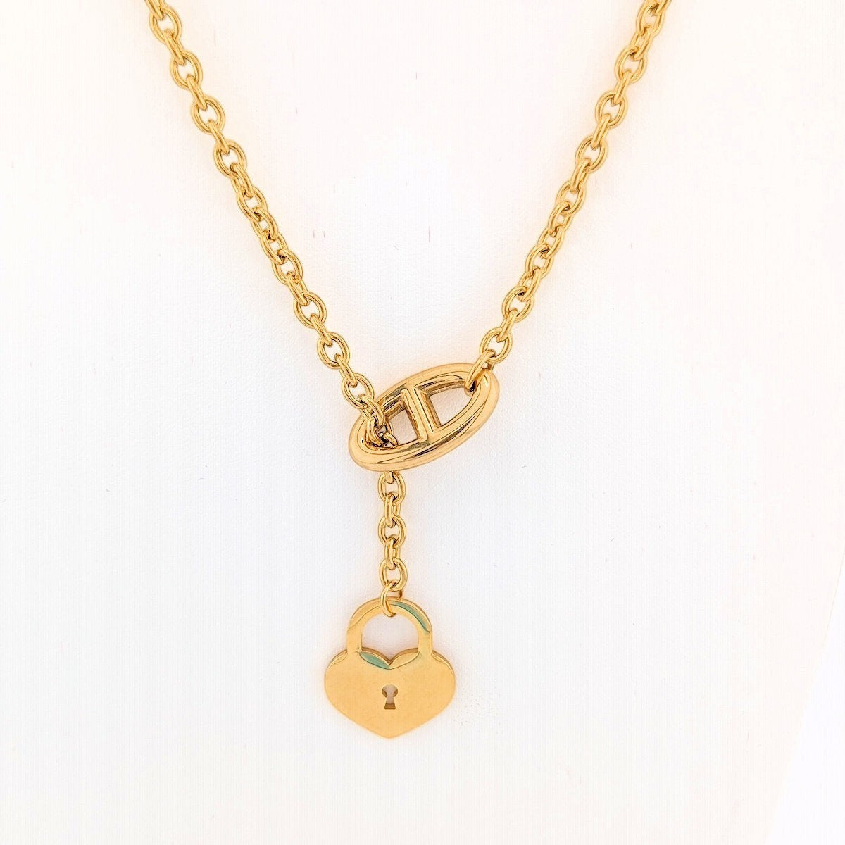 This 18K Gold plated, Stainless Steel chain necklace features a distinctive toggle closure and a heart-shaped padlock pendant